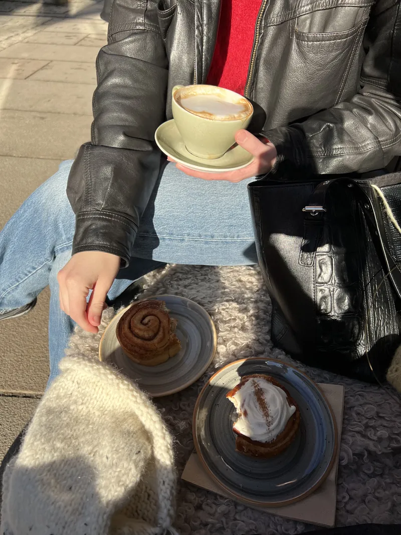 Kafébesøk med kaffe, kanelbolle og et hvitt strikketøy på fanget